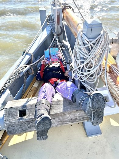 A crew member relaxing aboard My Alice with a book